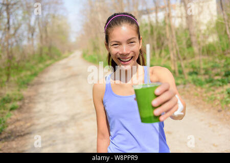 Grünes Gemüse Smoothies - gesunde Lebensweise und Ernährung Konzept. Nahaufnahme von grünes Gemüse detox Smoothie mit Spinat. Frau hand Gemüse-smoothies draußen im Wald. Stockfoto