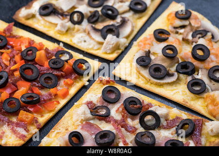 Sortierte Pizza Scheiben. Margherita, Salami, vier Käse Pizza. Ansicht von oben. Verschiedene Arten von Pizza auf die texturierte alten Holztisch Stockfoto