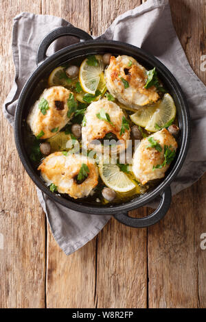 Griechische Küche cod Steaks mit Zitronen und Oliven closeup in einer Pfanne auf dem Tisch. Vertikal oben Ansicht von oben Stockfoto