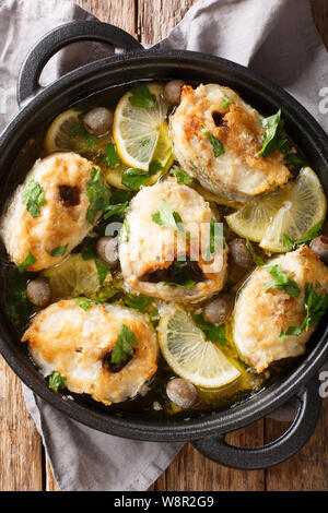 Würzige cod Steaks gebackene mit Zitronen und Oliven closeup in einer Pfanne auf dem Tisch. Vertikal oben Ansicht von oben Stockfoto