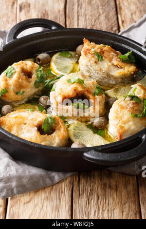 Griechische Küche cod Steaks mit Zitronen und Oliven closeup in einer Pfanne auf dem Tisch. Vertikale Stockfoto