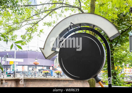 Schwarze runde Board leer im Freien, blur Gebäude und Bäume Hintergrund. Utrecht, Niederlande, historisches Zentrum. Werbung mockup Vorlage. Stockfoto