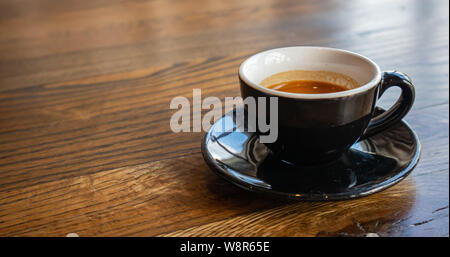 Espresso auf Holz. Espresso Tasse mit Untertasse, Schwarz Farbe auf Holz- Tabelle, kopieren Raum Stockfoto