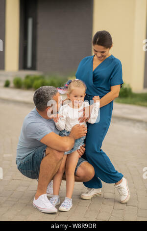 Liebevolle Eltern ihre strahlende niedlichen Tochter umarmen Stockfoto