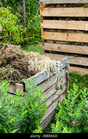 Holzkomposter, Kompost-Haufengarten, Trockenpflanzen und andere Bioabfälle auf Haufen, Kompost-Garten Stockfoto