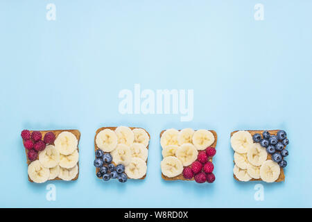 Gesundes Frühstück Sandwiches mit Erdnussbutter, Banane und Beeren auf einem hellen blauen Hintergrund. top Aussicht, Flach, kopieren Raum Stockfoto