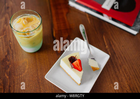 Ein Stück leckeren Kuchen mit Erdbeeren auf die Oberseite. Kalte frappe Neben. Stockfoto