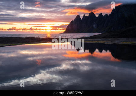 Reflexion in einem rockpool beeindruckende Oksen Bergkette bei sehr bunten Sonnenuntergang, Tungeneset, Senja, Norwegen Stockfoto