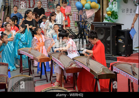 MISHAN, CHINA - Juli 28, 2019: Kinder in der chinesischen Tracht spielt Chinesische Musikinstrument-Gu Zheng gekleidet. Stockfoto