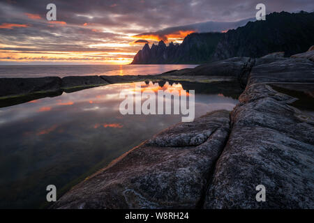 Reflexion in einem rockpool beeindruckende Oksen Bergkette bei sehr bunten Sonnenuntergang, Tungeneset, Senja, Norwegen Stockfoto