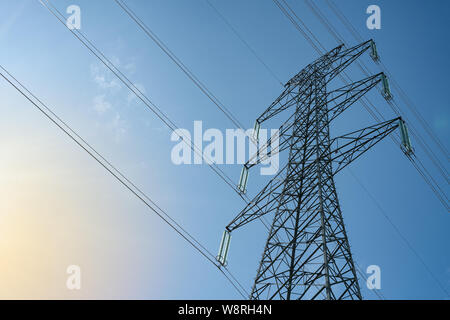 Elektrischen Freileitungen auf einem Sendemast gegen den blauen Himmel Hintergrund. Verteilung von elektrischer Energie Konzept. Stockfoto