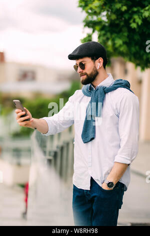 Junge, urbane, Geschäftsmann auf dem Smartphone zu Fuß auf der Straße mit "App sms sms-Nachricht auf dem Telefon Stockfoto