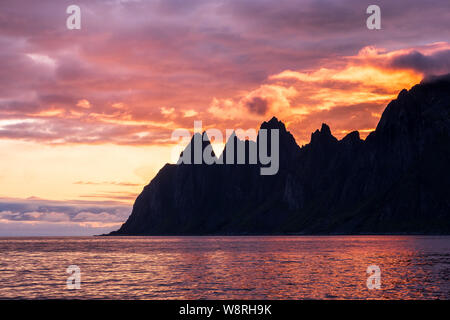 Blick über oksen Bergkette Teufel Kiefer bei Ersfjord in bunten beeindruckenden Sonnenuntergang, Senja, Norwegen Stockfoto