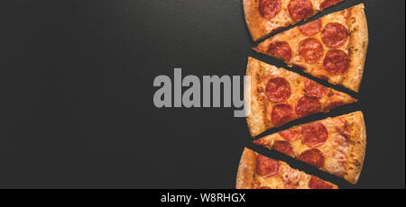 Pepperoni Pizza Slices auf schwarzen Hintergrund. Ansicht von oben mit der Kopie. Banner. Pizza essen Konzept Stockfoto