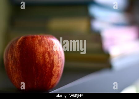Zurück zu Schule Konzept Hintergrund. Red Apple vor unscharfen Stapel von Büchern. Selektiver Fokus, kopieren Raum Stockfoto