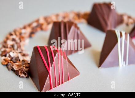 Bunte vegane Schokolade Pralinen und Kakaokerne auf Glas. Stockfoto