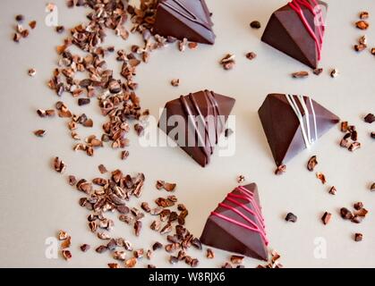 Bunte vegane Schokolade Pralinen und Kakaokerne auf Glas. Stockfoto