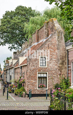 Elburg, Niederlande, 3. August 2019: Reihe von Häusern in der Altstadt gegen den ehemaligen Befestigungsmauer gebaut Stockfoto