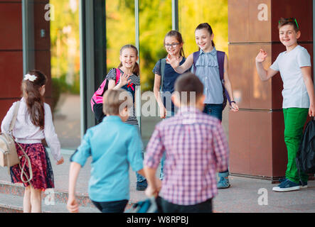 Mitschüler zur Schule gehen. Studenten begrüßen sich. Stockfoto