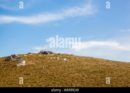 Der Hang bedeckt mit trockenem Gras und einige Steine auf dem Berg Nanos Stockfoto