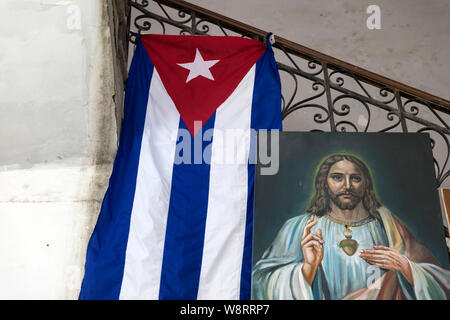 Innenraum der alten Spanischen Kolonialen Gebäude in Havanna. Eine große kubanische Flagge hängt neben einem alten Gemälde von Jesus Christus widerspiegelt, die nationalen Werte Stockfoto