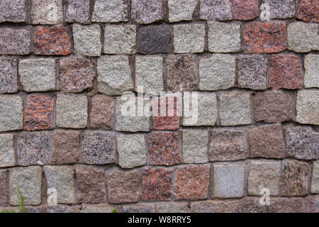 Stücke von Pflastersteinen Steine Pflastersteine aus Granit rot grau rosa Schwarz, Hintergrund Textur. Granit gemauerten Wänden der alten Gebäude. Stücke aus Granit Stockfoto