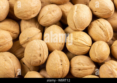 Stapel der Walnüsse in der Schale, Hintergrundbild close-up. Muttern strukturierten Nussbaum shell Textur. Gesund Eiweiß Mahlzeit Snack Stockfoto