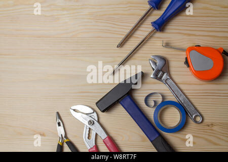 Reparatur Tools auf einem Holztisch. Hammer, Schraubendreher, Maßband Klebeband Schraubenschlüssel. Eine Reihe von Tools für die Reparatur von Geräten Stockfoto