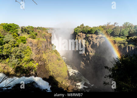 Der Regenbogen im Spray von Victoria Falls auf der Grenze zu Sambia und Simbabwe, Afrika. Stockfoto