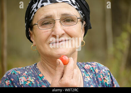 Gerne ältere Frau essen rote Pflaumen, gesunde Ernährung Konzept Stockfoto