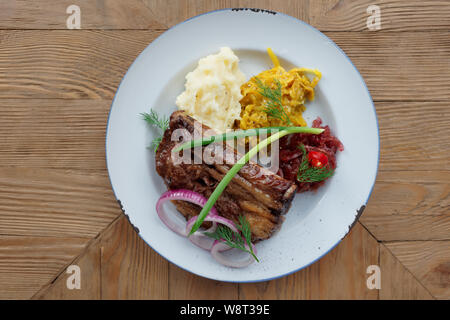 Gegrillte Rippchen mit Sauerkraut und Kartoffelbrei am Tisch im Restaurant Stockfoto