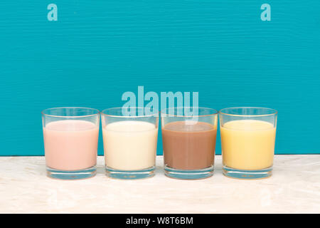 Aromatisiert Milchshakes - Erdbeere, Schokolade und Banane - und frische, cremige Milch in Glas Trinkgläser gegen eine blaugrüne Hintergrund Stockfoto