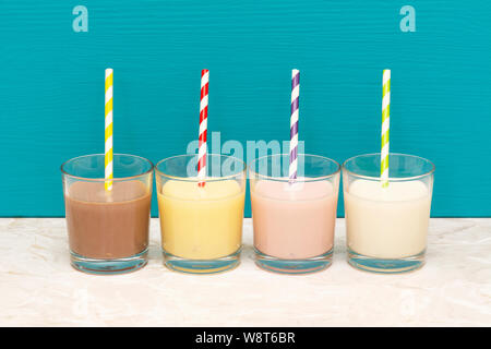 Schokolade, Bananen und Erdbeeren Milchshakes und frische Milch mit retro Papier Trinkhalme in Glas Trinkgläser mit einem teal Hintergrund Stockfoto