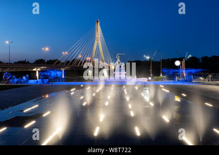 Polen, Warschau, Wassernebel der beleuchteten begehbaren Brunnen auf einem Platz, der von der Weichsel mit der Meerjungfrau und Swietokrzyski-brücke Stockfoto