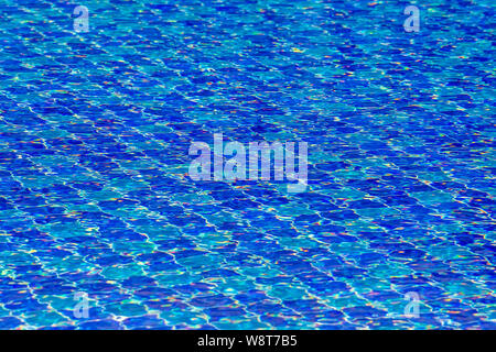 Wasser Wellen auf blau gefliesten Pool Hintergrund. Blick von oben. Blick auf den Pool vor dem Hotel. Wunderschöner Pool Bereit zum Urlaub Touristen. Stockfoto