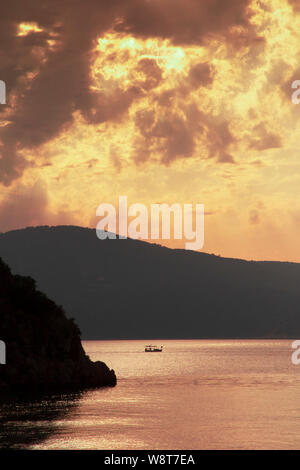 Ein Fischerboot kehrt zum Hafen unter dramatischen Himmel, wie die Sonne in der Nähe von Kalkan in Türkei Stockfoto