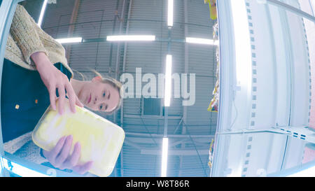 Frau mit gefrorenen Hähnchen im Supermarkt Stockfoto