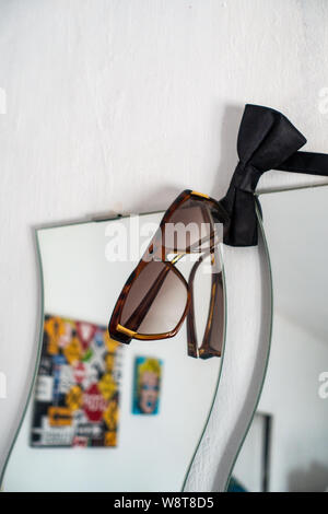 Studenten Sonnenbrille auf Schlafzimmer Spiegel eingehakt Stockfoto