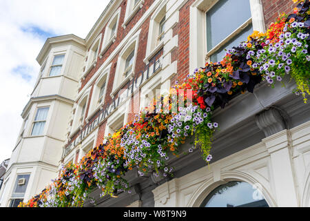 Hängende Körbe von Blumen auf der Vorderseite eines Hotels angezeigt Stockfoto