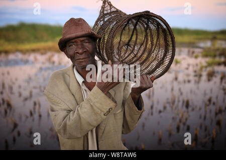 Fischer trägt eine fischfalle am Ufer des Lake Malawi. Malawi ist eines der ärmsten Länder der Welt. Stockfoto