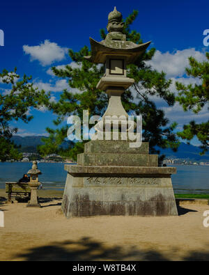 Traditionelle und eindrucksvollen japanischen Stein Laterne am Ufer der Insel Miyajima bei guter Witterung erfasst erstellt einen tropischen Bild Stockfoto