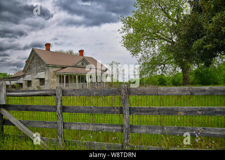 Verlassenen Bauernhaus mit hölzernen Zaun und großen Baum im Hof Stockfoto