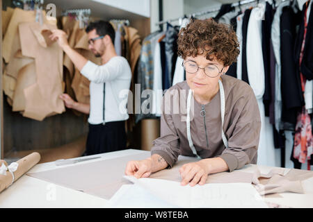 Junge zuversichtlich Modedesigner auf Skizze auf Papier während der Arbeit Stockfoto