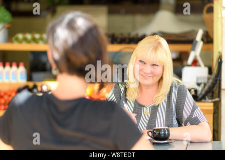 Junge gedrückt Frau im Gespräch mit Psychologen während der Sitzung, psychische Gesundheit. Psychotherapeut mit Patienten im Cafe. Porträt Frau mittleren Alters professionelle Makler oder Berater Beratung junge Happy girl. Stockfoto