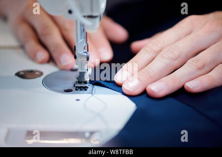 Hände von professionelle Schneiderin holding Stück Stoff in der Nähe Nähnadel Stockfoto