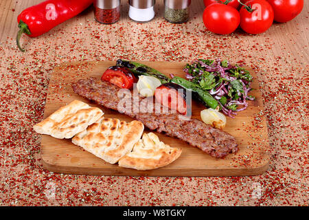 Berühmte Türkische Orfa Fried Kebab mit Full Service mit Tomaten und frischem Gemüse auf einem Tisch mit aromatischen Gewürzen gefüllt Stockfoto