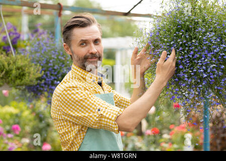 Erfolgreich im mittleren Alter Gärtner im Vorfeld steht die kleine blühende Blumen Stockfoto