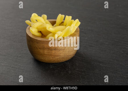 Menge ganze rohe Nudeln Gemelli in Houten auf grauem Stein Stockfoto