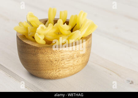 Menge ganze rohe Nudeln Gemelli in Houten auf weißem Holz Stockfoto