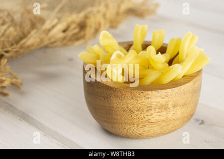 Menge ganze rohe Nudeln Gemelli in Houten mit Jute-stoff auf weißem Holz Stockfoto